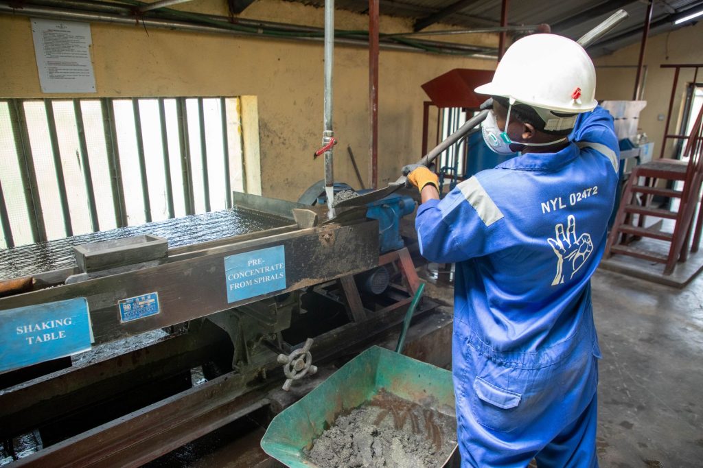 Brasil cria política para transformar minerais críticos em tecnologia e indústria Trabalhador usando uma mesa vibratória para processar minério em uma instalação industrial.