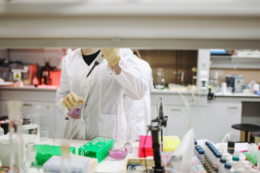Cientista de jaleco manuseia amostras em um laboratório de pesquisa.