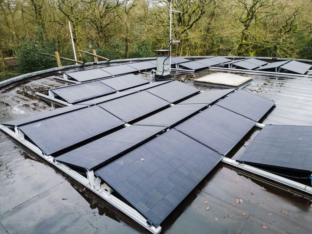 5º leilão do Eco Invest Brasil aprova R$ 49,95 bilhões para inovação e transformação ecológica Painéis solares instalados no telhado de uma edificação, cercados por vegetação.